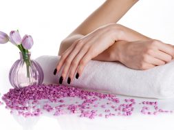 Spa manicure treatment: woman hands with dark manicure lying down on a white terry towel