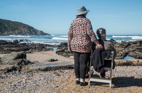 woman-standing-beside-woman-on-white-wooden-chair-facing-160767