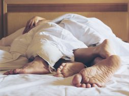 Couple on white bed in hotel room focus at feet