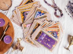 Tarot cards spread face up on white cloth sheet with wooden tray, lavender, candles and attributes. Top view. Minsk, Belarus, 27.09.2021