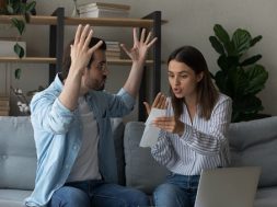 Stressed emotional couple arguing fighting when checking financial papers together finding unexpected debt lack of money on bank account. Mad angry husband scolding wife for overspending family budget