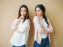 Young upset girls friends in casual offended at each other isolated on the beige background jealousy