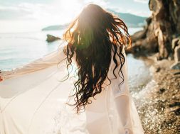 girl running dreamy with wind in hair and sunflare on beach sunset. defocus