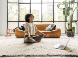 Young multiracial latina woman meditating at home with online video meditation lesson using laptop. Meditation and spirituality concept.