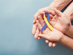 Adult and child hands holding blue and yellow ribbon shaped paper, Down syndrome awareness , World down syndrome day